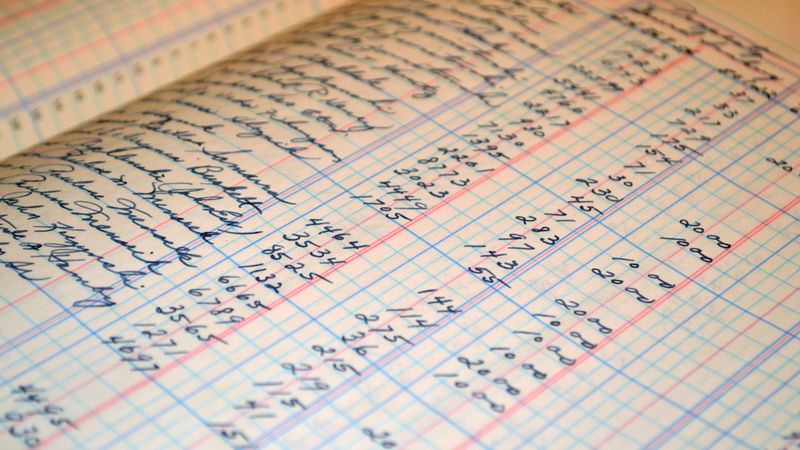 Bilan comptable, calculatrice et stylo posés sur un bureau