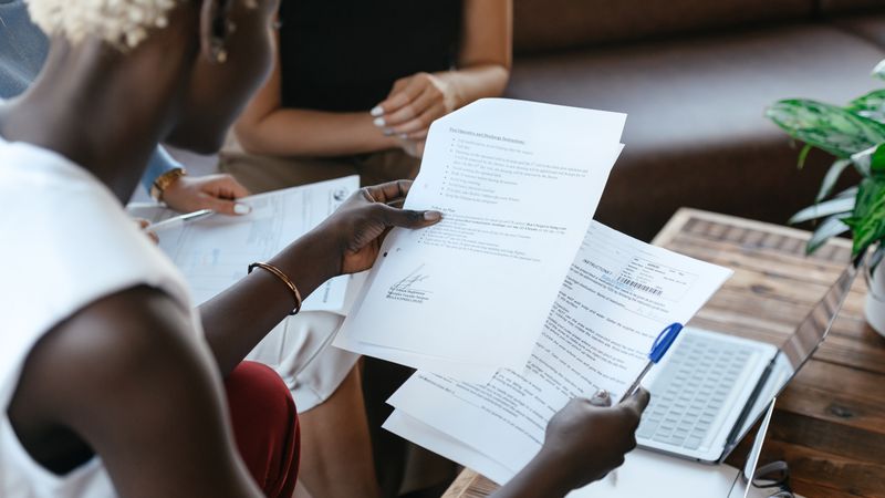 Créateur d'entreprise comparant trois dossiers de statuts juridiques posés sur un bureau