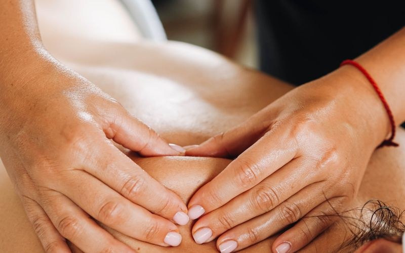 Mains d'un praticien massant le dos d'un client lors d'une séance
