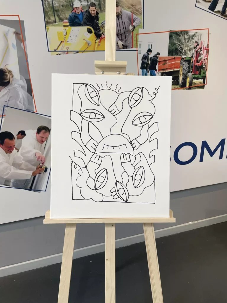 Participants autour d'une table peignant ensemble une toile au trait sur chevalet